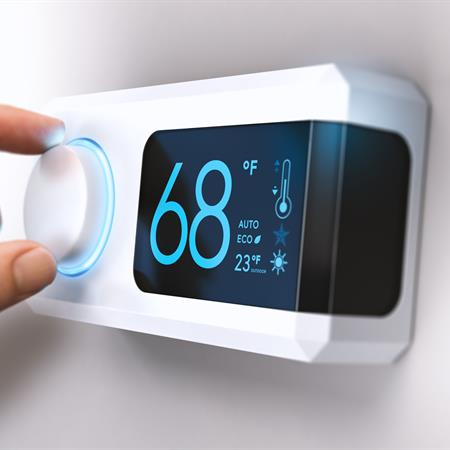 Hand turning down thermostat set at 68 degrees